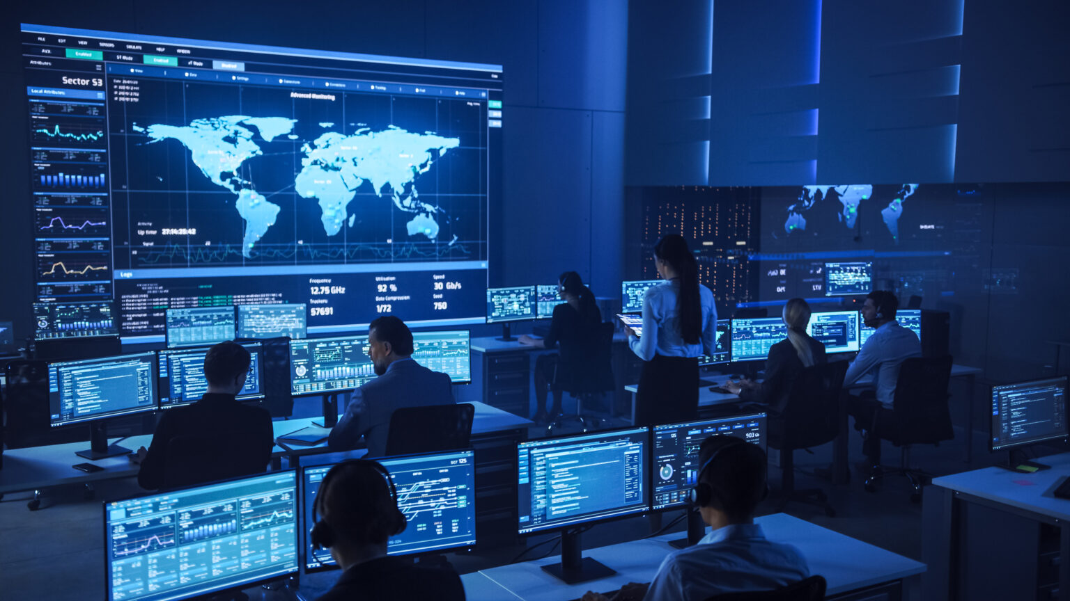 Team of Professional Computer Data Science Engineers Work on Desktops with Screens Showing Charts, Graphs, Infographics, Technical Neural Data and Statistics. Low Key Control and Monitoring Room.